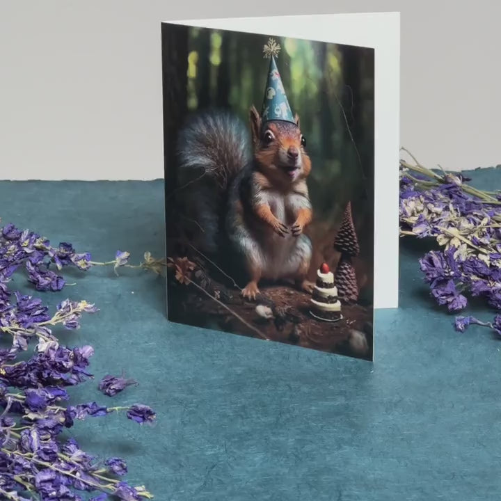 Augmented reality birthday card with a grey squirrel wearing a party hat in front of a tiny birthday cake in a forest